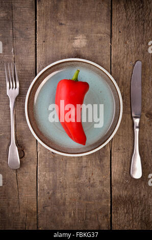 Red pepper on a blue plate on rustic wood Stock Photo
