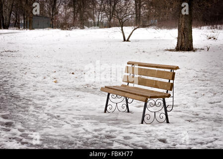 A lonely bench in the park covered by snow in winter, Kiev, Ukraine Stock Photo