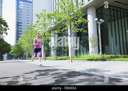 Young Japanese woman running downtown Tokyo Stock Photo