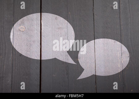 Two white text balloons on dark black wooden background Stock Photo