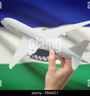 Airplane in hand with national flag on background series - Lesotho Stock Photo