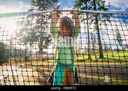 Girl standing on tennis court lifting net Stock Photo