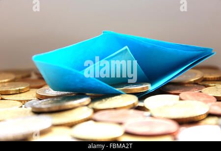 Paper boat sinking in a sea of euro coins Stock Photo