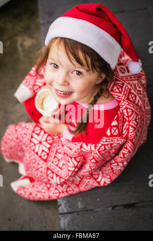 Girl wrapped in festive blanket holding a mug of  hot cocoa Stock Photo