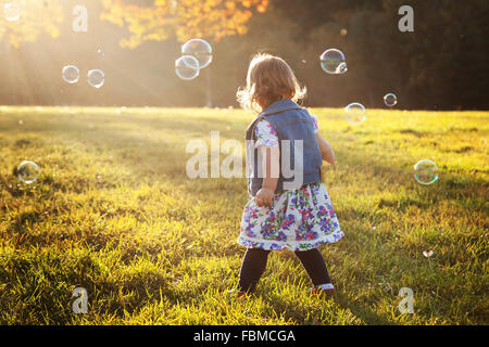 Girl in park surrounded by soap bubbles Stock Photo