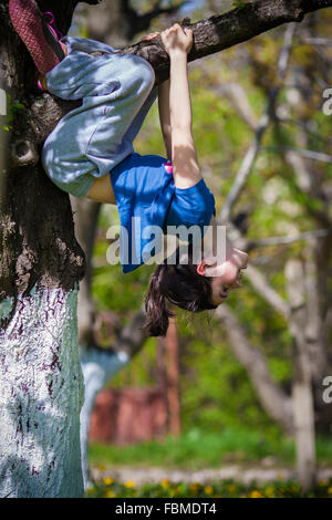 Young girl hanging upside down in a tree Stock Photo