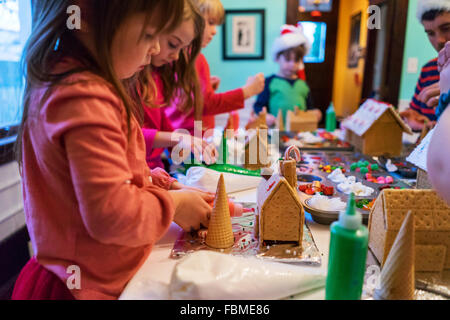Children decorating gingerbread houses with candy and frosting Stock Photo