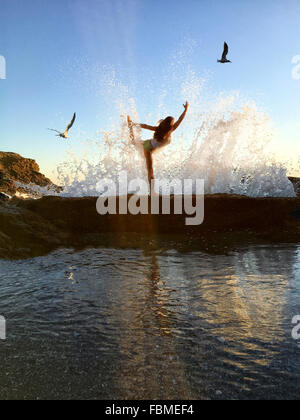 woman in still bow yoga pose on cliffs at beach fbmef4