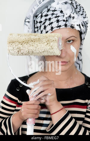 Woman holding paint roller in front of face Stock Photo