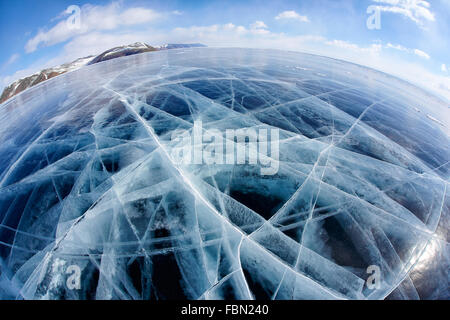 Wide angle shot with fisheye lens of winter ice landscape on Siberian lake Baikal with dramatic weather clouds on blue sky backg Stock Photo