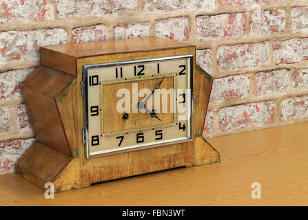 Vintage art deco wooden mantel clock with old brick wall effect background Stock Photo