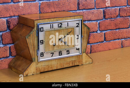 Vintage art deco wooden mantel clock with old red brick wall effect background Stock Photo