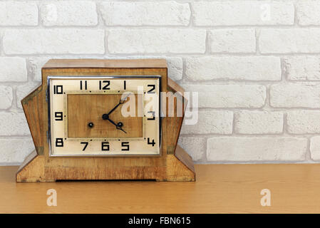Vintage art deco wooden mantel clock with old white brick wall effect background Stock Photo