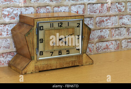 Vintage art deco wooden mantel clock with old brick wall effect background Stock Photo
