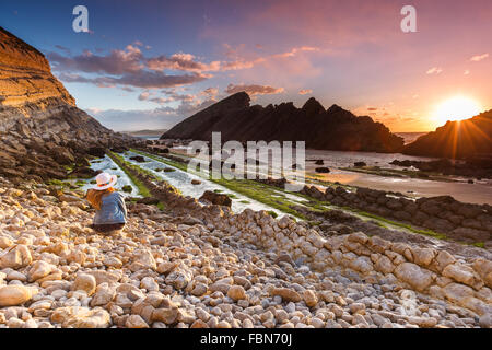 A caucasian young woman at El Madero beach by twilight. Liencres, Cantabria, Spain. Stock Photo