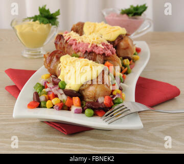 Chicken leg wrapped in bacon with vegetables and different sauces to them Stock Photo