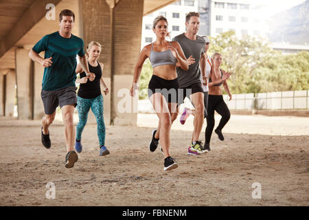 Determined  group of young people running together in city. Running club members training together. Stock Photo