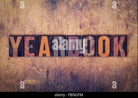 The word "Yearbook" written in dirty vintage letterpress type on a aged wooden background. Stock Photo