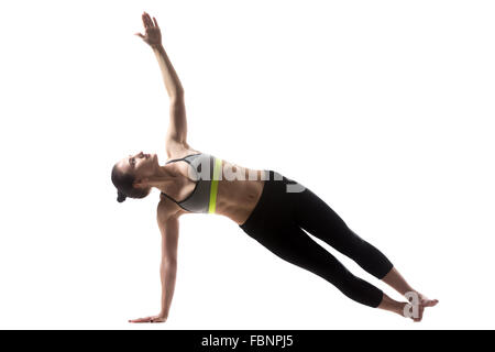 Portrait of sporty beautiful young brunette woman in sportswear working out, doing Side Plank Posture, Pose of Vashista Stock Photo