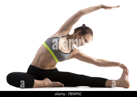 Portrait of sporty fit happy beautiful young woman in sportswear bra and black pants working out, doing Revolved Head to Knee Stock Photo