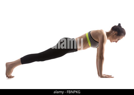 Sporty fit beautiful young brunette woman in sportswear bra and black pants working out, doing push-ups, Phalankasana, Plank Stock Photo