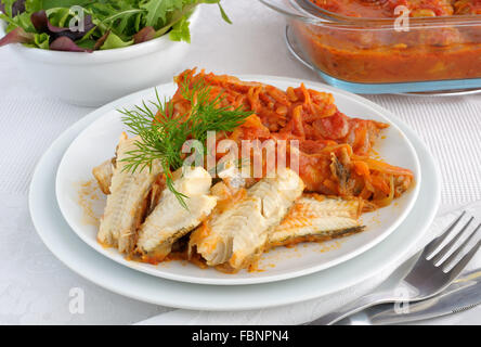 Marine fish baked with onions and carrots in tomato sauce Stock Photo