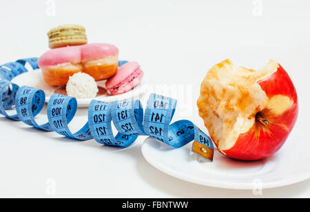 new diet concept, question sign in shape of measurment tape between red apple and donut isolated on white Stock Photo