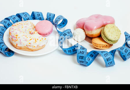 new diet concept, question sign in shape of measurment tape between red apple and donut isolated on white Stock Photo