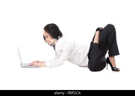 Business, study, healthy lifestyle. Smiling young female office employee in formalwear lying in yoga pose typing Stock Photo