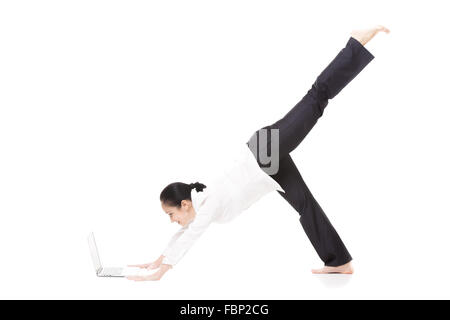 Business, study, healthy lifestyle. Smiling young office female in formalwear standing in yoga position Eka Pada Adho Mukha Stock Photo