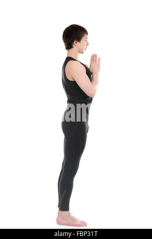 Profile of sporty young man practicing yoga, standing with hands joined in Namaste gesture, focusing, Anjali mudra, Pranamasana Stock Photo