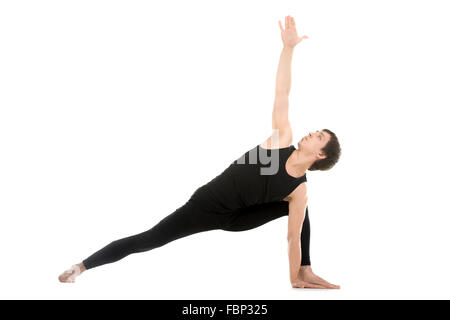 Sporty young man practicing yoga, doing stretching exercise, Extended Side Angle Pose, Utthita Parsvakonasana, therapeutic Stock Photo