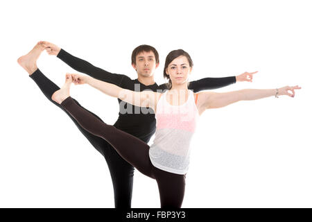 Two sporty people practice yoga with partner, couple doing stretching exercise, Extended Hand to Big Toe yoga pose, Utthita Hast Stock Photo