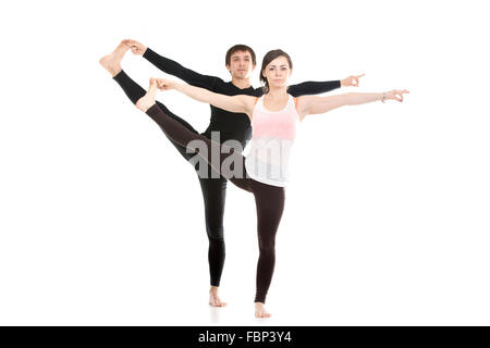 Two sporty people practice yoga with partner, couple doing stretching exercise, Extended Hand to Big Toe yoga pose, Utthita Hast Stock Photo