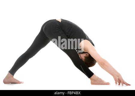 Profile of sporty young man working out, standing in yoga Pyramid Pose, Parsvottanasana deep variation, exercise for shoulders Stock Photo