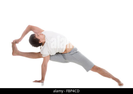 Sporty young man working out, standing in Vishvamitrasana Side bend, Visvamitra Pose, full length studio shot Stock Photo