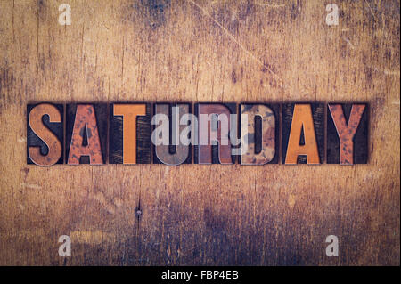 The word 'Saturday' written in dirty vintage letterpress type on a aged wooden background. Stock Photo