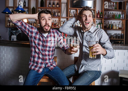 Young people with beer watching football in a bar Stock Photo