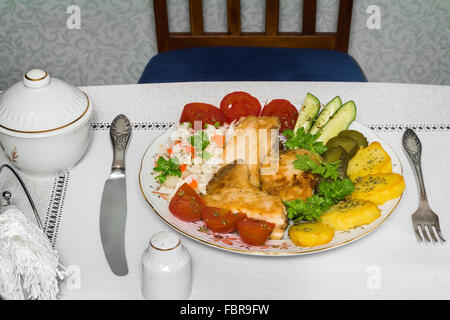 On the table is a plate with pieces of delicious fried fish and various basimi. Stock Photo