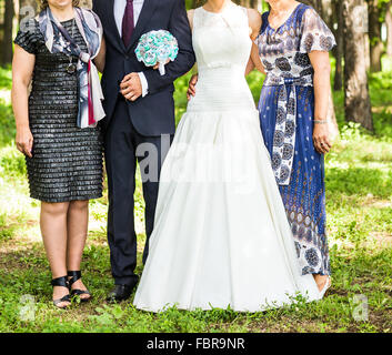 newlywed couple  with guests  in green sunny park Stock Photo