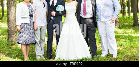 newlywed couple  with guests  in green sunny park Stock Photo