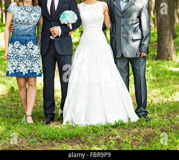 newlywed couple  with guests  in green sunny park Stock Photo