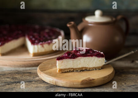 Classic New York style cheesecake with teapot. Slice of sweet on wooden table Stock Photo