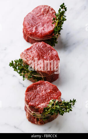 Raw fresh marbled meat Steak filet mignon and thyme on white marble background Stock Photo