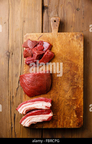 Different types of Raw fresh meat on cutting chopping board block on wooden background Stock Photo