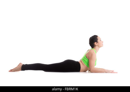 Sporty yoga girl on white background doing easy variation of cobra asana, Sphinx Pose, half Cobra posture, Ardha bhudjangasana Stock Photo