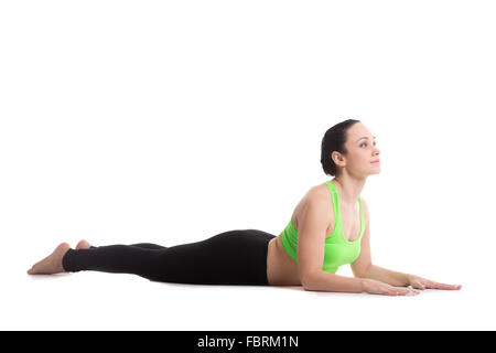 Sporty yoga girl on white background doing exercises for spine, simple variation of cobra asana, Sphinx Pose, half Cobra posture Stock Photo
