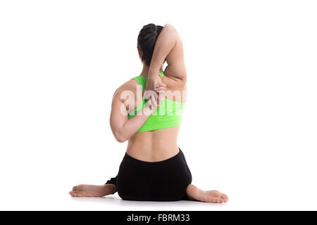 Sporty girl doing yoga training, sitting in Gomukhasana, Cow face pose, asana for stretching triceps, shoulders Stock Photo