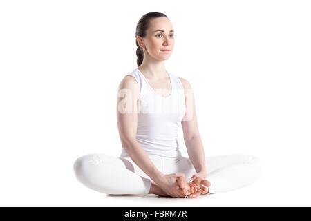 Sporty beautiful smiling young woman in white sportswear sitting in baddha konasana, bound angle, cobbler, butterfly pose Stock Photo