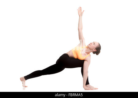 Beautiful sporty girl in bright orange sportswear practicing yoga, doing lunge exercise, Revolved Side Angle Pose, Parivrtta Stock Photo